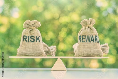 Risk reward ratio risk management concept Risk and reward bags on a basic balance scale in equal position depicts investors use a risk reward ratio to compare the expected return of an investment